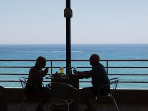 Deux personnes sont assises à une table, face à l’océan.