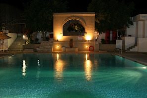 A swimming pool with a stone archway and steps leading up to it.