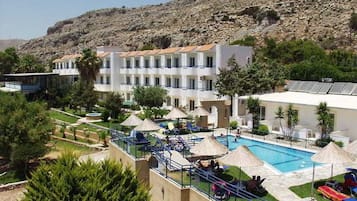 Ein Hotel mit Pool, Liegestühlen und einem Bergpanorama.