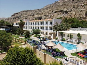 A hotel with a pool, sun loungers, and a mountainous backdrop. - Ilyssion (Rhodes)