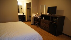 A hotel room with a bed, a desk with a chair, a television, and a microwave. - Eden Valley Motel (Eden Valley)