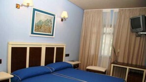 Ein Hotelzimmer mit einem Bett, Nachttischen, einem Fernseher und einem Bild an der Wand.
