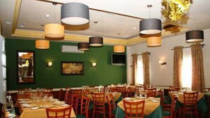 Un restaurant doté de nombreuses tables et chaises, d’un mur végétal et de luminaires suspendus.