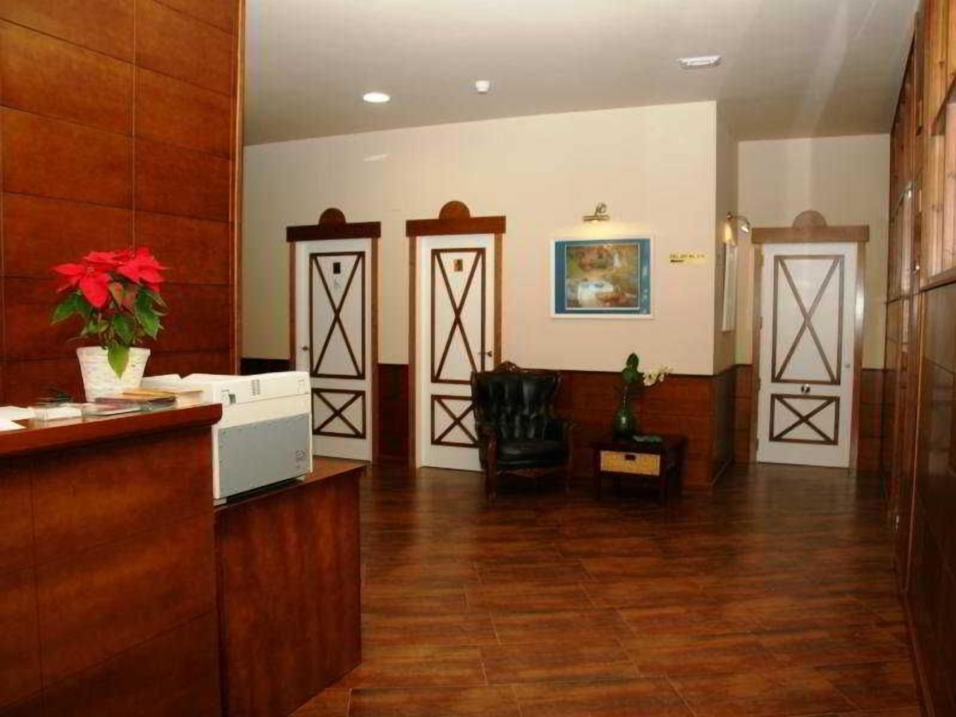 Una zona de recepción con un mostrador de madera, una butaca de cuero negro y un cuadro en la pared.