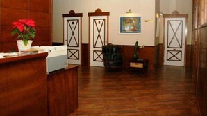 Un espace d’accueil avec un comptoir de réception en bois, un fauteuil en cuir noir et un tableau accroché au mur.