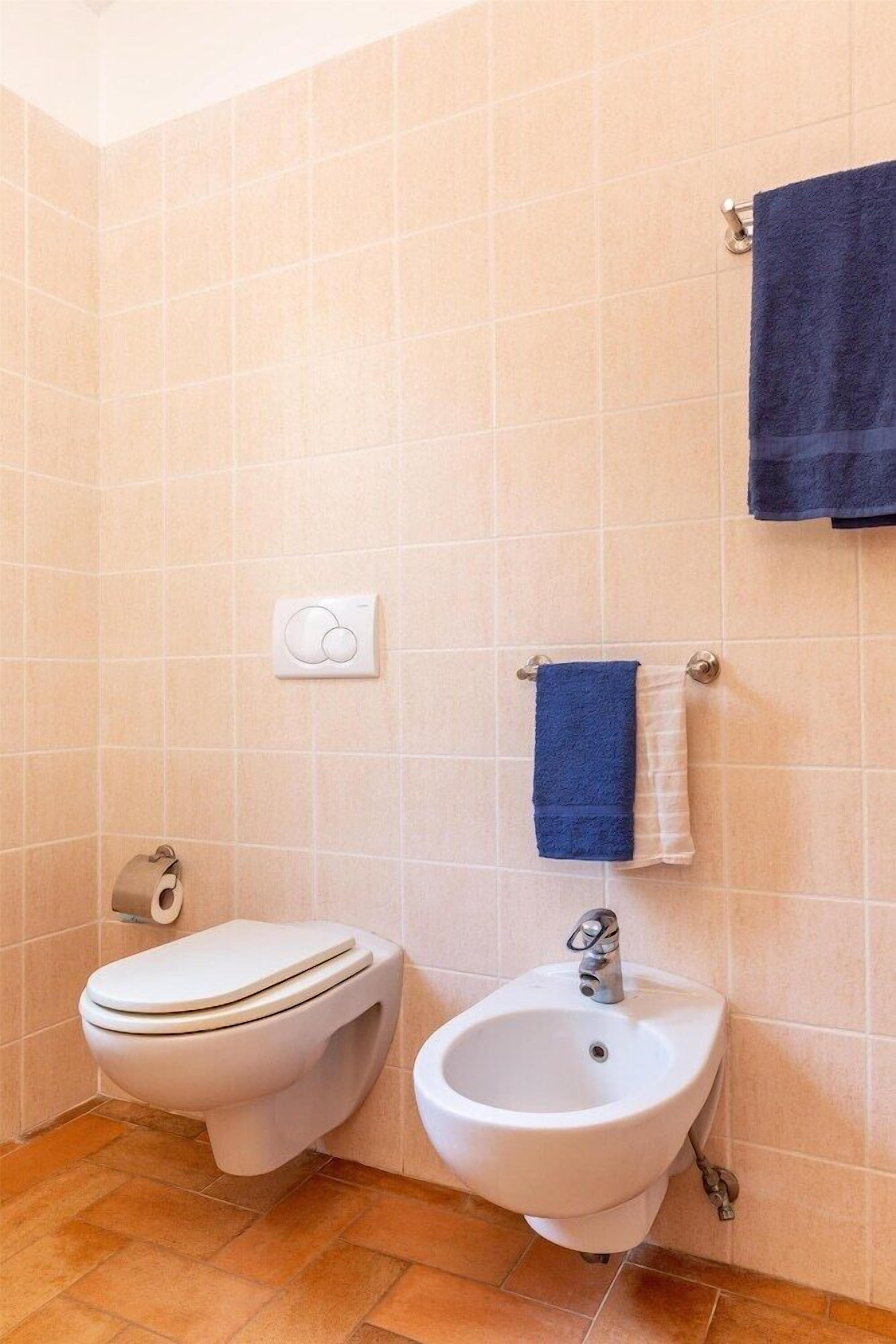 Un baño con inodoro, bidé y toallero.