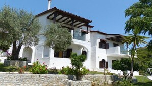 Un edificio blanco de dos pisos con tejado de tejas, paredes de piedra y balcones.