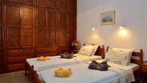 Una habitación de hotel con dos camas, un armario de madera y un cuadro en la pared.