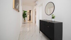 Un couloir avec un meuble noir, un miroir rond et une plante en pot.