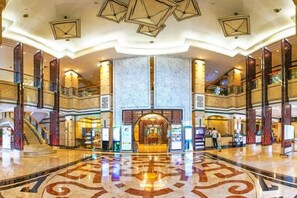 Un'ampia hall con pavimento in marmo centrale, diversi livelli e una maestosa scalinata.