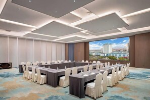 Un salón de conferencias con una larga mesa, sillas y vistas a la ciudad.