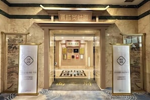 A hotel entrance with a marble floor and a sign above the door.