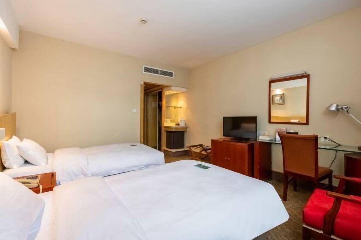 A hotel room with two beds, a desk with a computer, a TV, and a mirror.