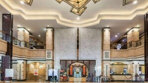 Eine großzügige Lobby mit einer zentralen Rezeption, mehreren Stockwerken und einem modernen Chandelier-Design.