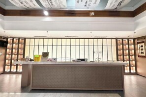 Un comptoir d’accueil au design moderne, une grande fenêtre avec des stores et un mur doté d’étagères verticales.