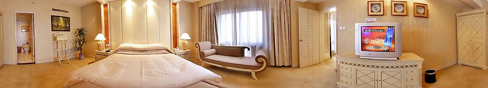Quarto de hotel com cama grande, sofá, televisão e armário.