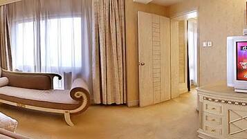 Quarto de hotel com cama grande, sofá, televisão e armário.