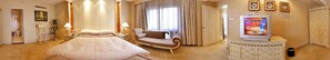 Una camera d'albergo con un letto grande, un divano, una televisione e un armadio.