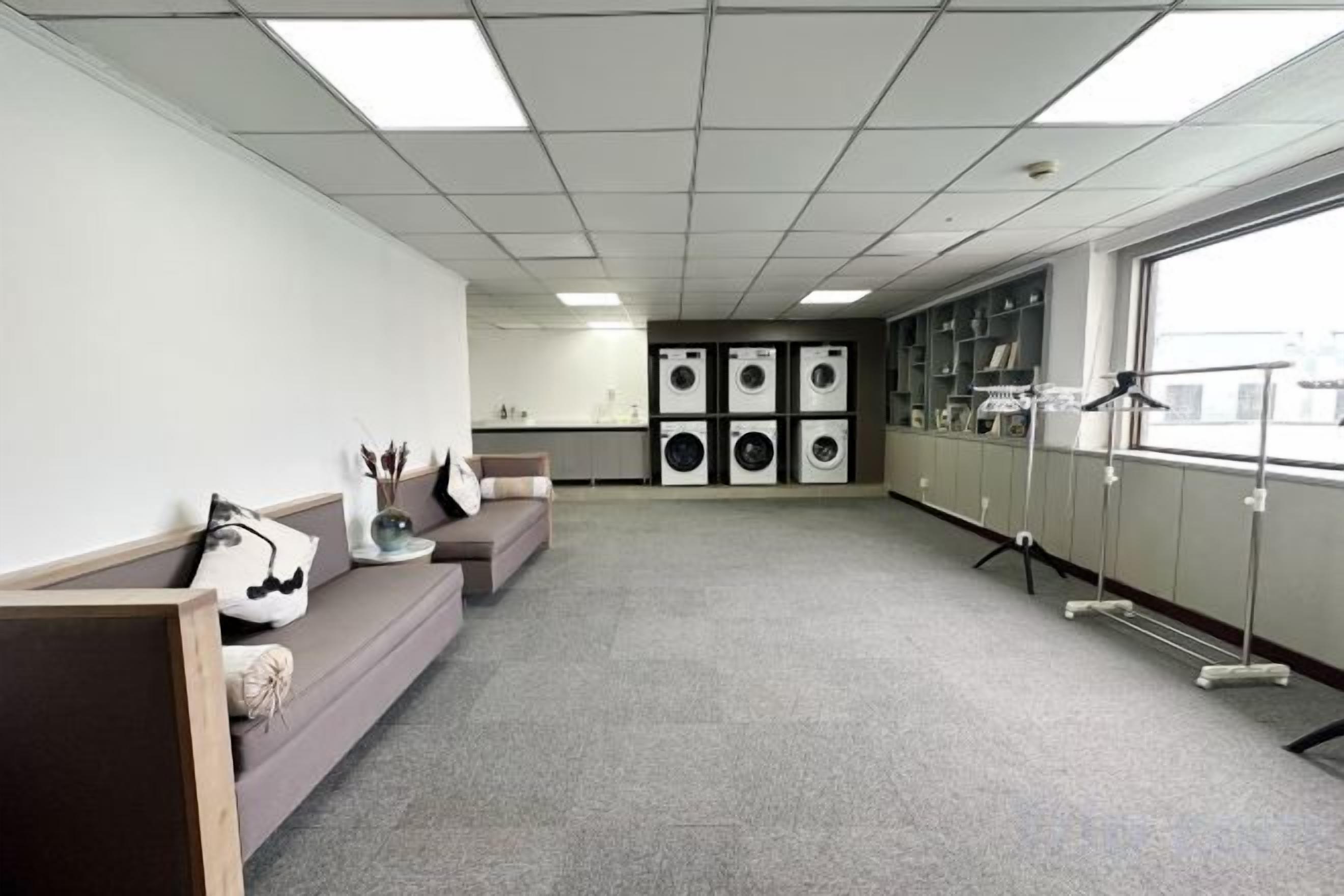 A room with a sofa, a washing machine, and a window.