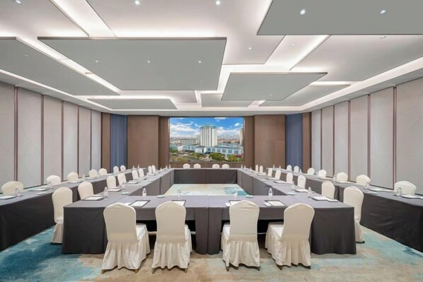 Un salón de conferencias con una larga mesa, sillas y vistas a la ciudad.