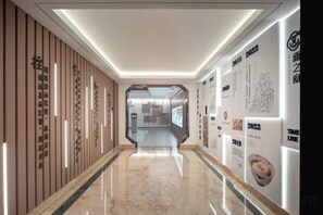 A hallway with a polished floor, wooden paneling on one side, and wall-mounted advertisements. - Suzhou Castle Scholars Hotel (Suzhou)