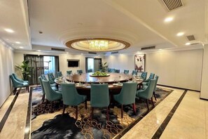 A conference room with a round table, chairs, and a chandelier. - Suzhou Castle Scholars Hotel (Suzhou)