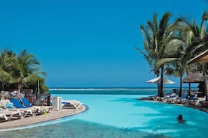 A clear blue pool with lounge chairs and palm trees, overlooking the ocean. - Baobab Beach Resort (Diani Beach)