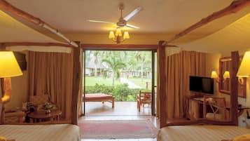 Habitación de hotel con cama, televisor, escritorio y vista a un jardín.