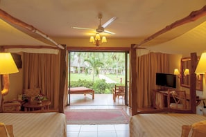 Habitación de hotel con cama, televisor, escritorio y vista a un jardín.