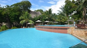 A swimming pool with lounge chairs and umbrellas, surrounded by palm trees and a mountainous backdrop. - Baobab Beach Resort (Diani Beach)