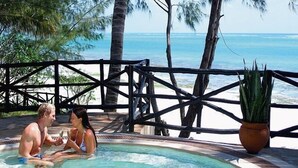 A couple in a hot tub with a view of the ocean and a wooden fence. - Baobab Beach Resort (Diani Beach)