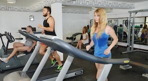 Un gimnasio con cintas de correr, pesas y equipo de ejercicio.