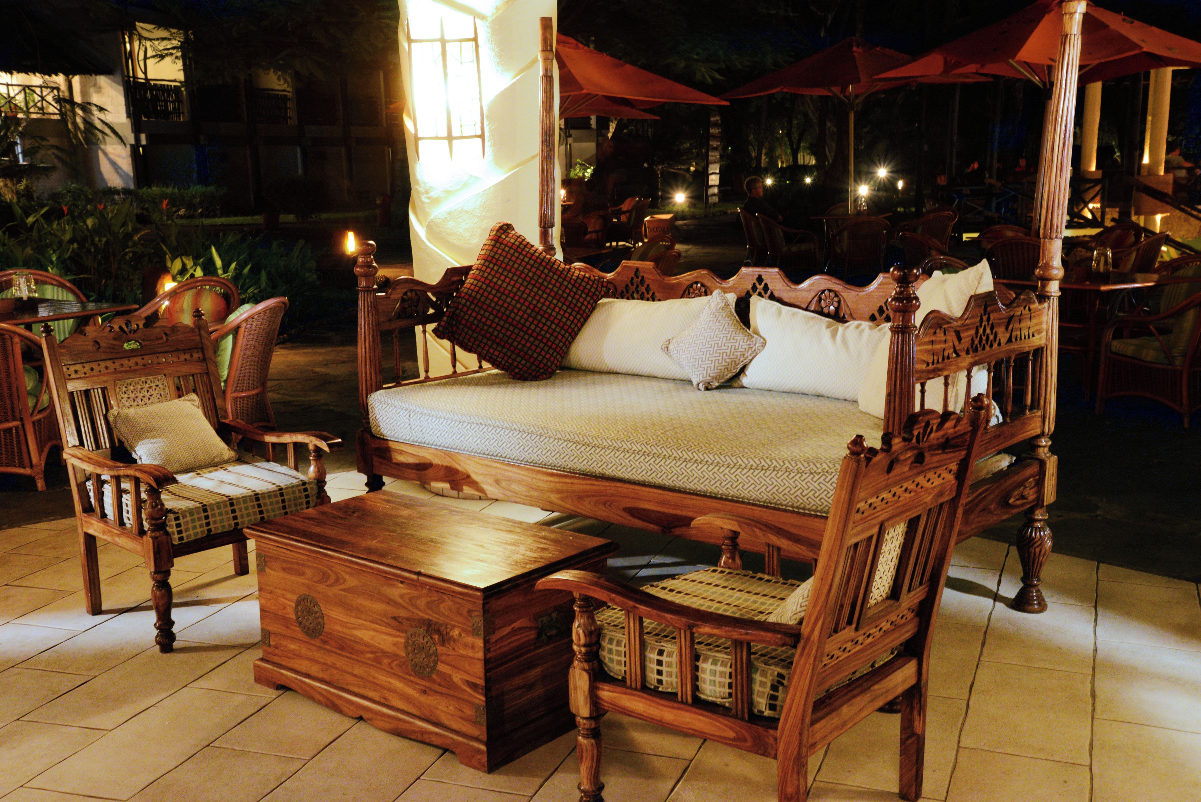 Un espace extérieur aménagé avec des meubles en bois, comprenant un auvent, des chaises en osier et une table en bois.
