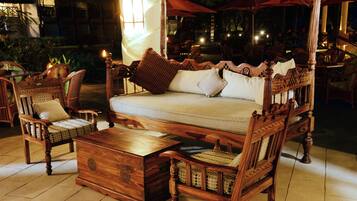 Un espace extérieur aménagé avec des meubles en bois, comprenant un auvent, des chaises en osier et une table en bois.