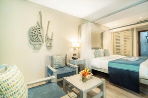 A hotel room with a bed, a chair, a small table with a vase of flowers, a nightstand, a lamp, and a mirror. - Baobab Beach Resort (Diani Beach)