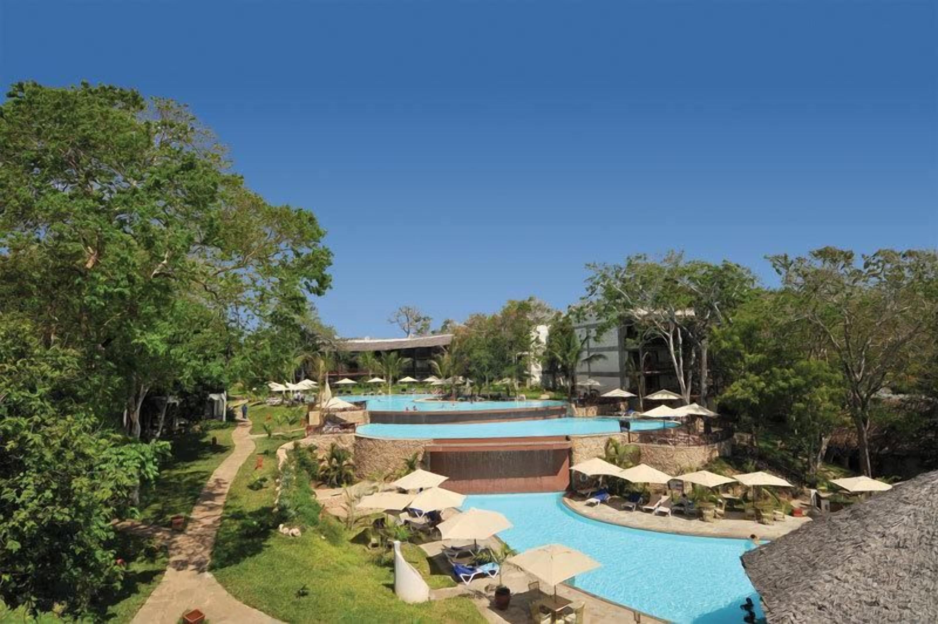 A resort with multiple swimming pools, lounge areas with umbrellas, and lush greenery.