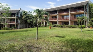 A multi-story hotel with a thatched roof, balconies, and a well-maintained lawn. - Baobab Beach Resort (Diani Beach)