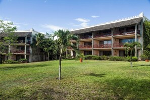 A multi-story hotel with a thatched roof, balconies, and a well-maintained lawn. - Baobab Beach Resort (Diani Beach)