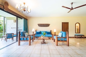 Un salon spacieux avec un canapé bleu, une table basse en bois et un ventilateur de plafond.