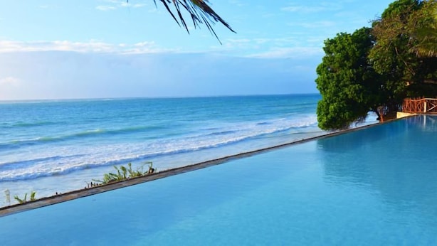 A clear view of a swimming pool with a view of the ocean and a tree-lined area. - Baobab Beach Resort (Diani Beach)