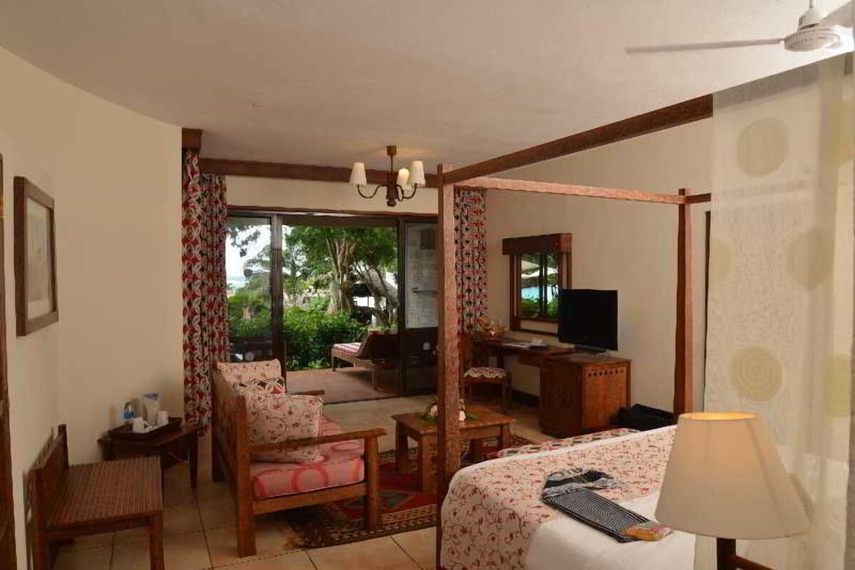 A hotel room with a bed, a desk, a chair, a television, and a view of the outdoors.