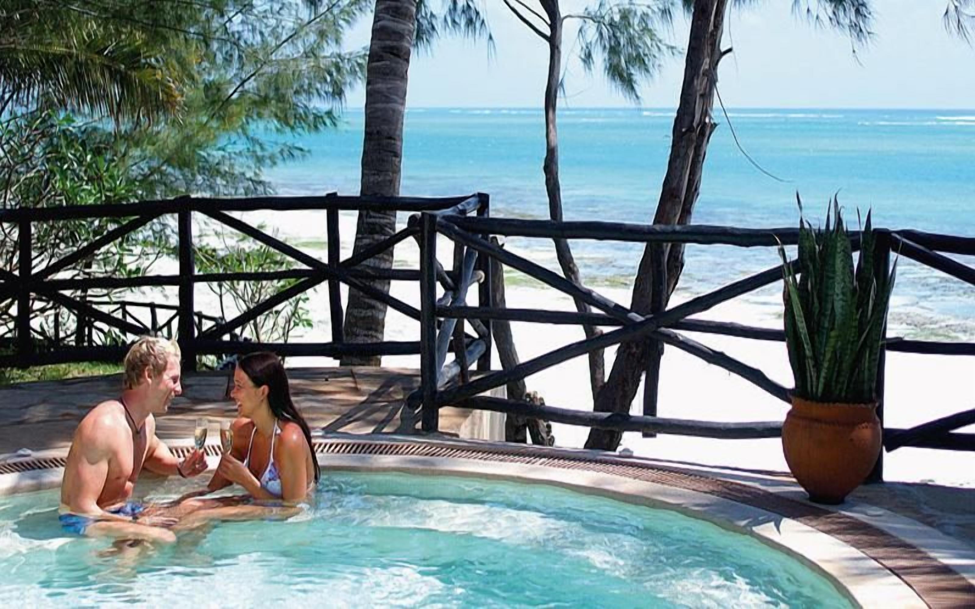 Ein Paar sitzt in einer Hot Tub mit Blick auf den Ozean und einem Holzzaun.