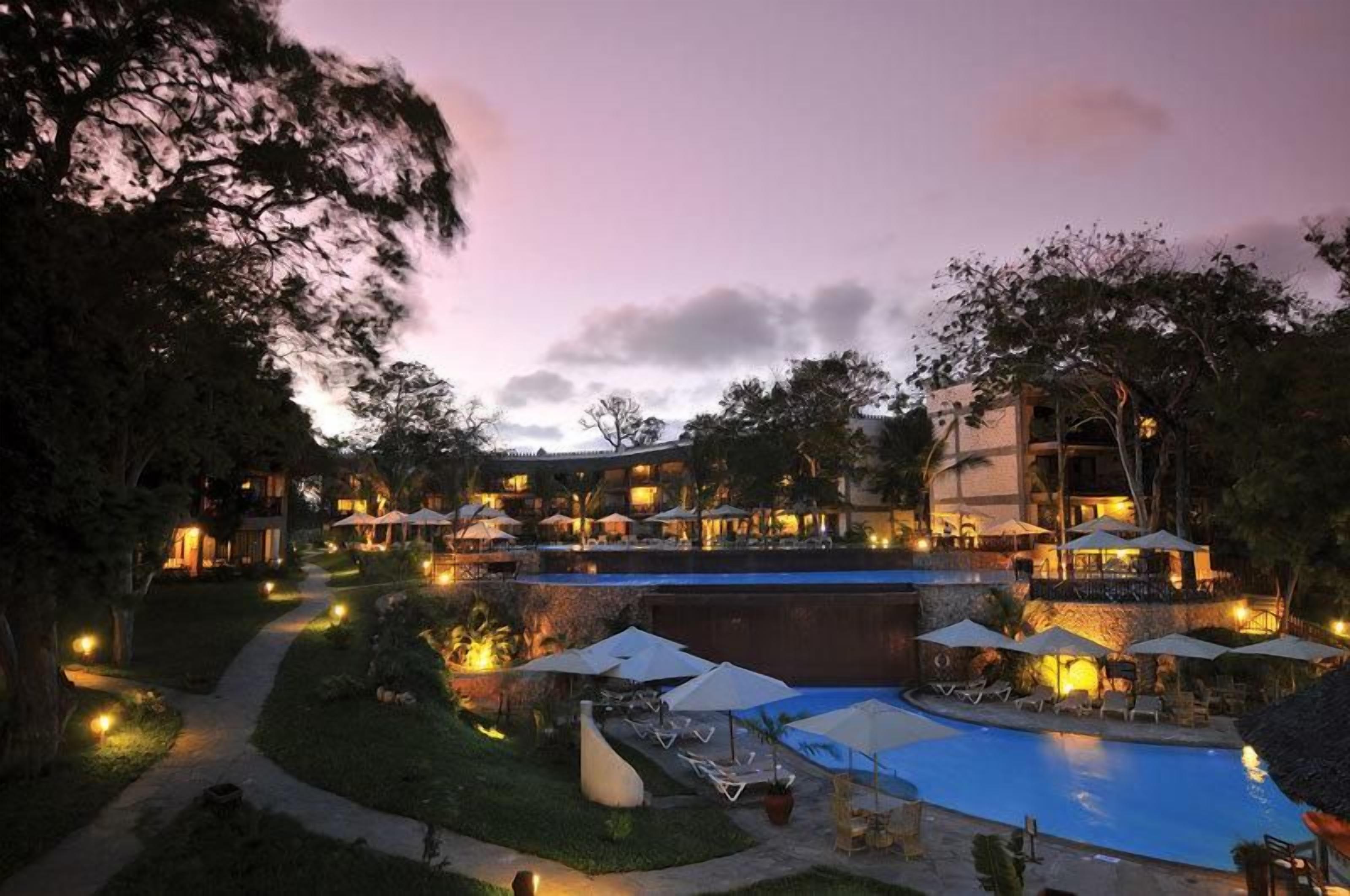 Un resort con piscina, sillas de descanso y sombrillas.