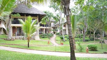 A resort with thatched-roof buildings, palm trees, and a well-maintained garden.