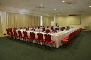 A conference room with a long table, red chairs, and water bottles. - Baobab Beach Resort (Diani Beach)