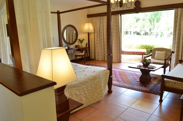 Habitación de hotel con cama, escritorio, silla, mesa con un florero y vistas al exterior.