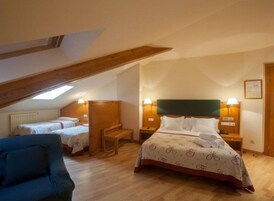 Un dormitorio con una cama grande, dos camas más pequeñas, un banco y una silla.