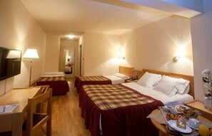Habitación de hotel con dos camas individuales, un escritorio, una silla, un televisor y una bandeja para el desayuno.