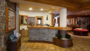 A reception area with a stone counter, wooden ceiling, and a bench with magazines. - Bonavida (Canillo)