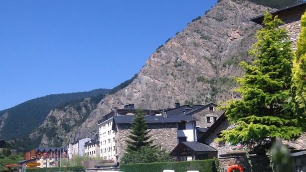 A swimming pool with lounge chairs, surrounded by greenery and a mountain backdrop. - Bonavida (Canillo)